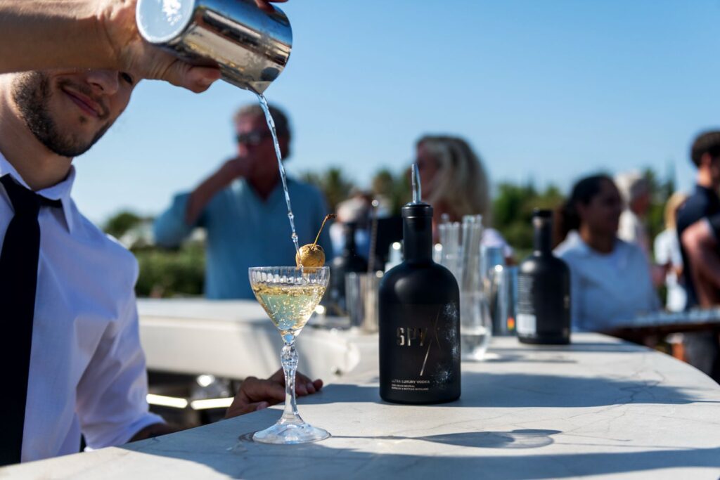 bartender pouring spy x ultra luxury vodka into a cocktail glass decorated with a golden cherry